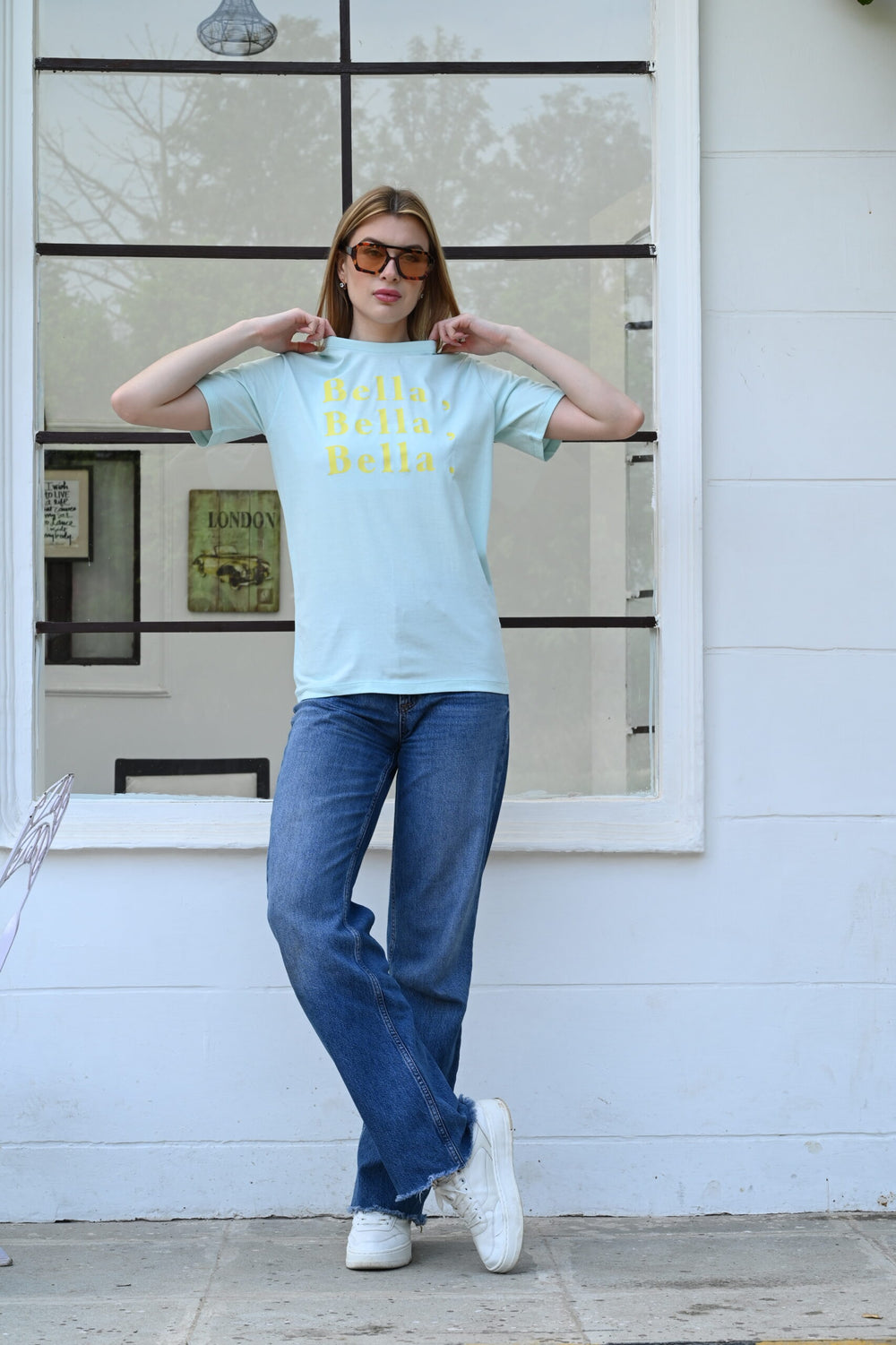 Woman wearing light blue cotton t-shirt with yellow “Bella, Bella, Bella.” slogan – casual fashion style